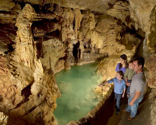 Emerald Lake is one of many large, natural pools found within Natural Bridge Caverns. The green color comes from the diffraction of light waves passing through the water.